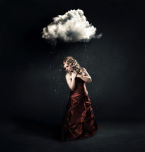 A woman in a red dress standing under a tiny cloud with rain drops.
