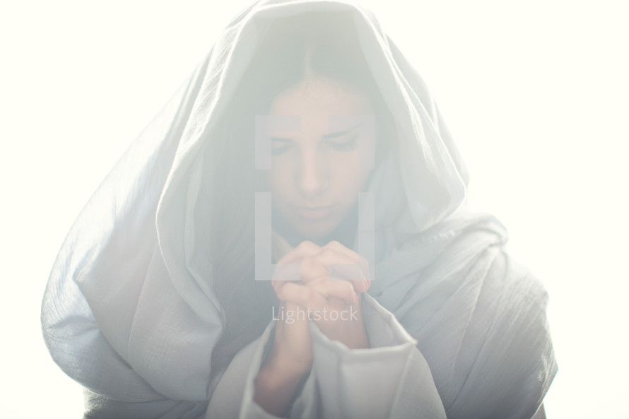 Mary in a blue shroud in bright light with praying hands 