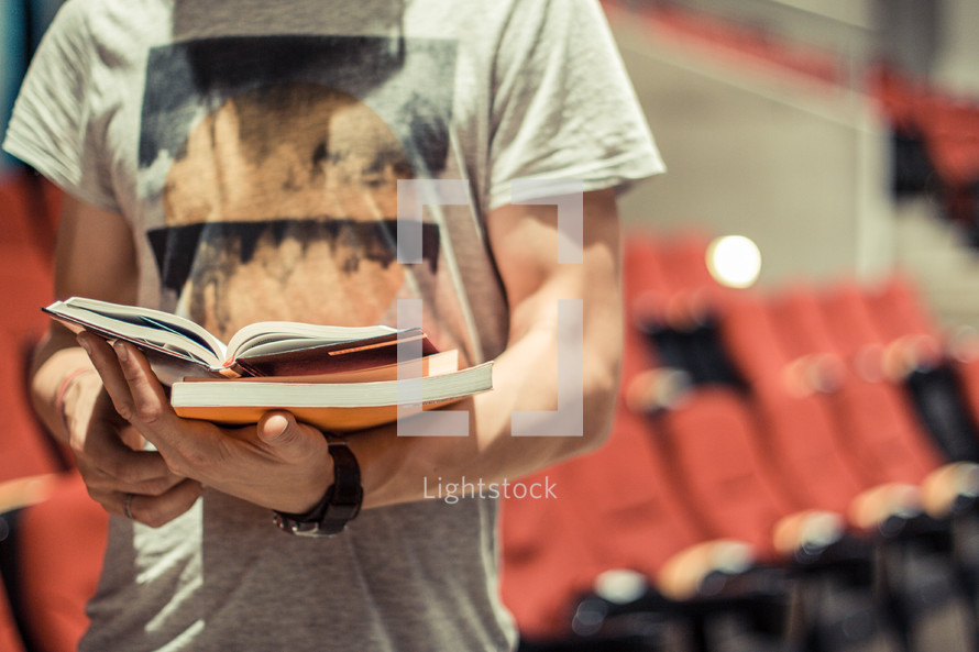 Man reading a book in an auditorium.