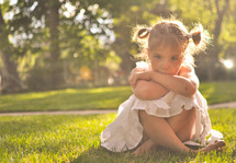 a toddler girl sitting in the grass 