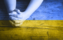 praying hands overlayed with the colors of Urkrainian flag 