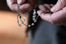 elderly man praying a rosary 