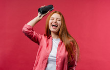 Woman dancing, enjoying on pink studio background. Girl moves to rhythm of music. Young teenager listening to music by wireless portable speaker - modern sound system. High quality