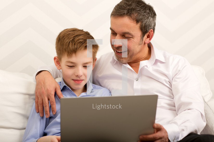 Boy and father using laptop together