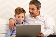 Boy and father using laptop together