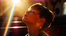 Portrait of a young boy with his eyes closed in the sunlight.