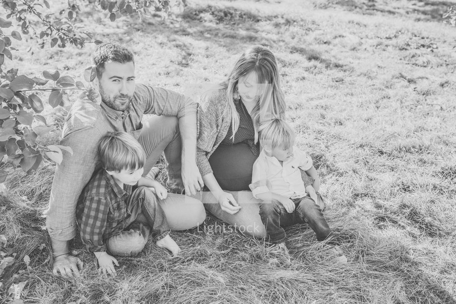 a young family sitting in the grass 