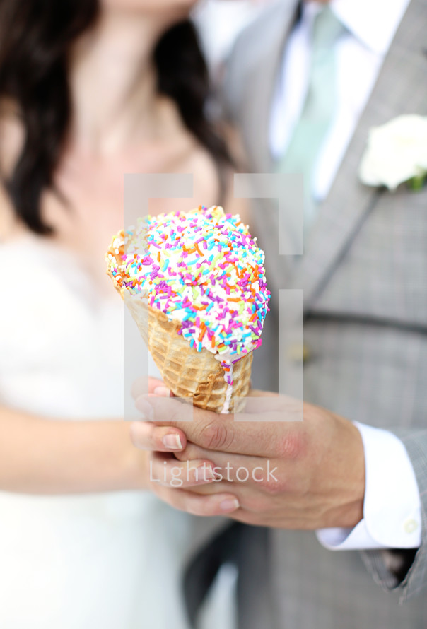 bride and groom holding a sprinkled waffle cone 