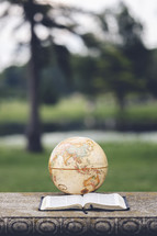 a globe and open Bible outdoors 