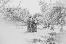 a family sitting in an apple orchard 