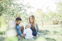 a family sitting in an apple orchard 
