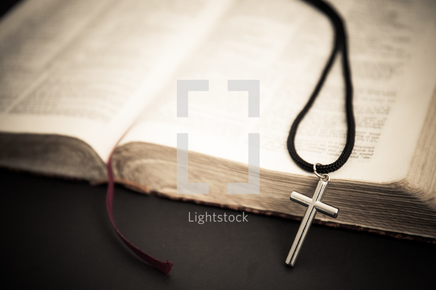 cross of necklace on the pages of a Bible 