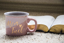 Mom Fuel coffee mug and open Bible 