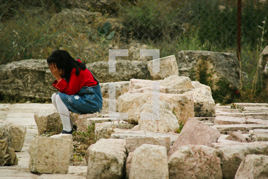 a little girl sitting on rocks crying 