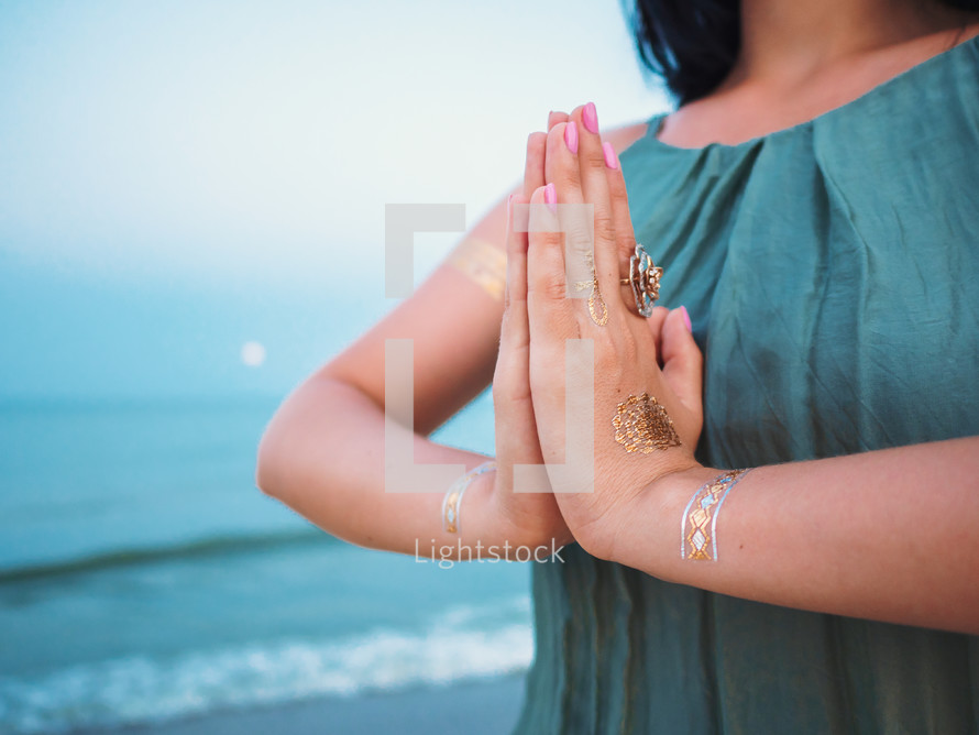 Silver and golden flash tattoo on female hands over sea or ocean background