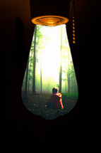 view of a boy sitting in a forest in a lightbulb 