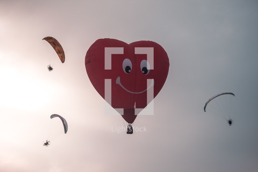 heart shaped hot air balloon and parachuters 