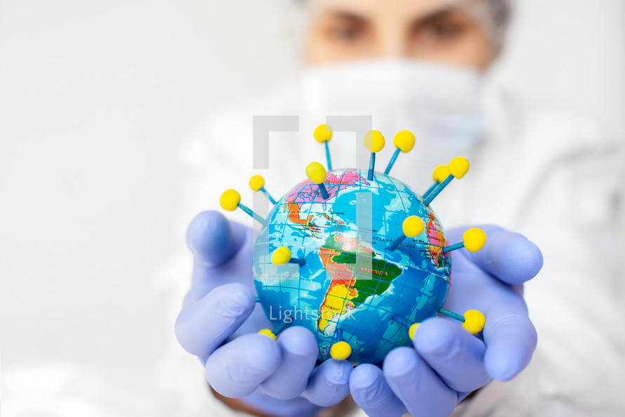Coronavirus pandemic in world, woman scientist holding in her hand the earth globe that is shaped like a coronavirus