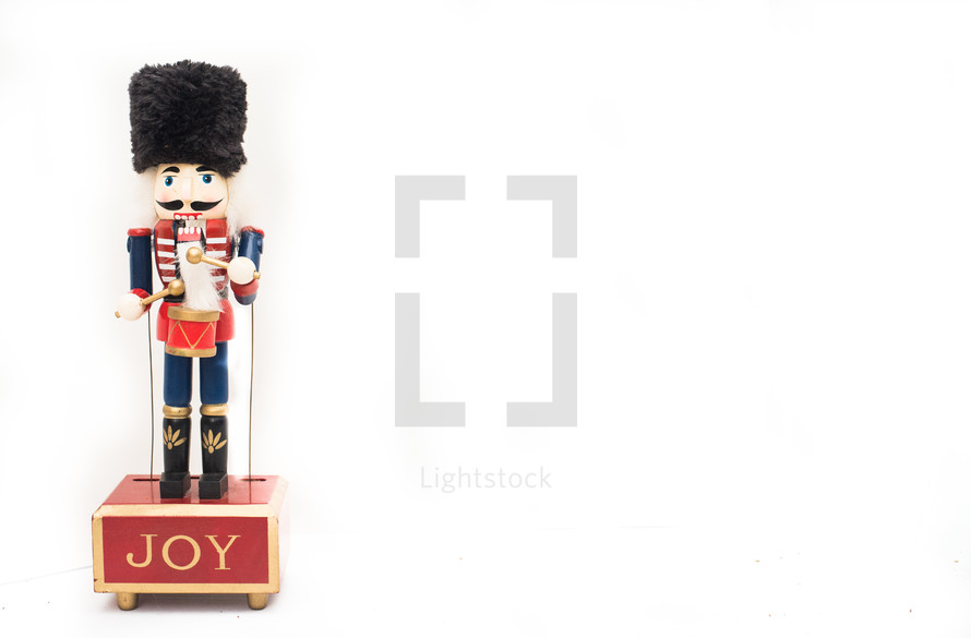 A small nutcracker doll against a plain white background with copy space or negative space.