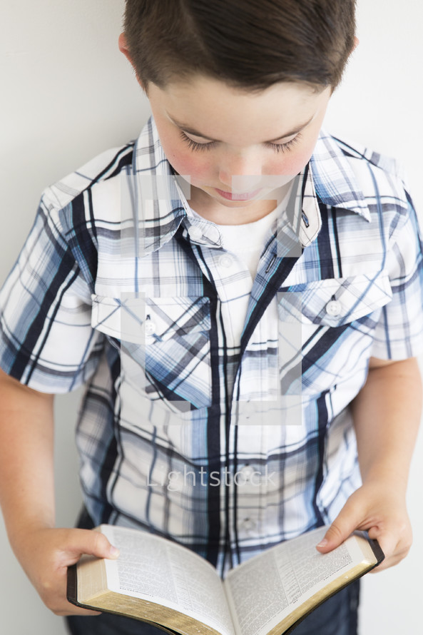 a boy child reading a Bible 