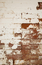 white pealing paint on a red brick wall 