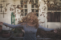 A girl throwing fall leaves in the air
