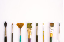 Paintbrushes lined up on a white background.