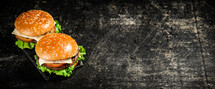 A burger on a stone board on a table. On a black background. High quality photo