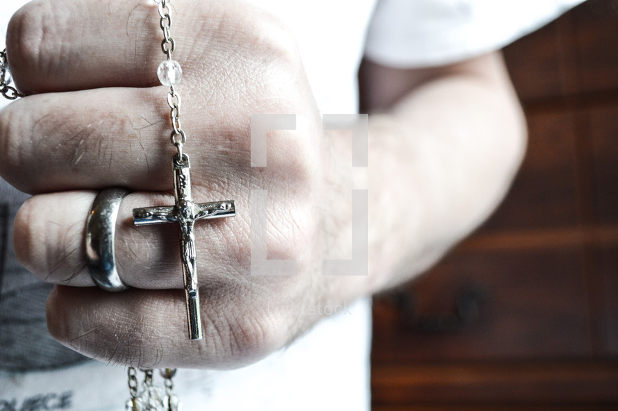 man's hand holding a rosary 