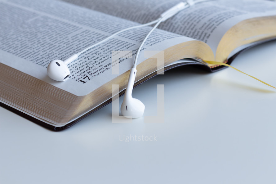 earbuds on the pages of an open Bible 