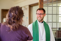 priest greeting a woman with a handshake 
