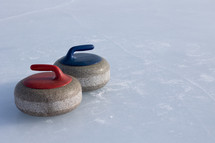 Two curling rocks on ice