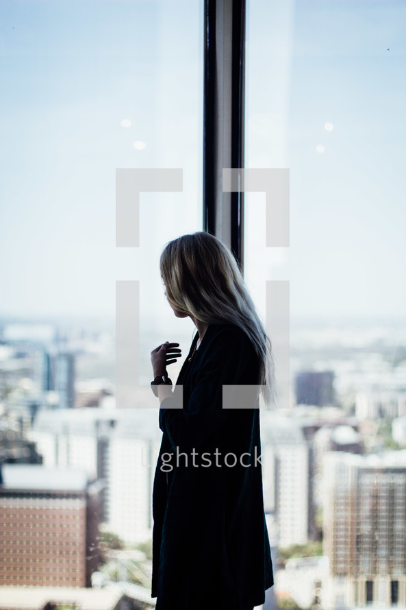 a woman looking out a window at a city 