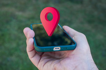 hand holding a smart phone with a location symbol