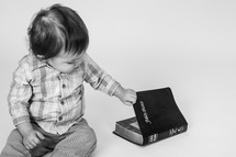 toddler boy opening a Bible 