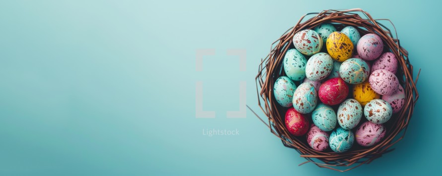Colorful pastel easter eggs in a nest on blue background. Happy Easter concept.