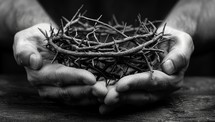 Black and white image of a crown of thorns held in hands.