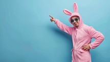 Young man in a pink bunny costume and sunglasses on a blue background