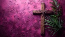 Wooden cross with palm leaf on grunge pink background. Copy space
