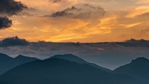 Golden sky with fast moving clouds over spring mountains at sunrise timelapse
