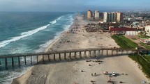ocean pier in Rosarito and people riding horses on a beach 