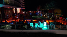 Group of people hanging out at night on a rooftop pool side lounge with the DJ