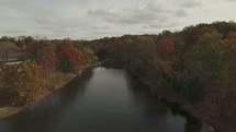 aerial view of a drone flying over a river and fall forest 