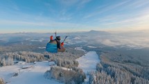 Paragliding flying above snowy forest mountains at sunrise in winter wonderland nature, freedom flight adrenaline

