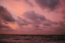 pink clouds in the sky over the ocean 