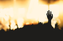 silhouette of a raised hand at a concert 