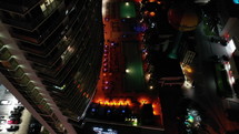 Aerial Top-down pedestal of groups of people hanging out at  night on a rooftop poolside lounge with DJ