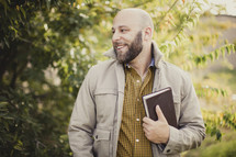 man holding a Bible outdoors