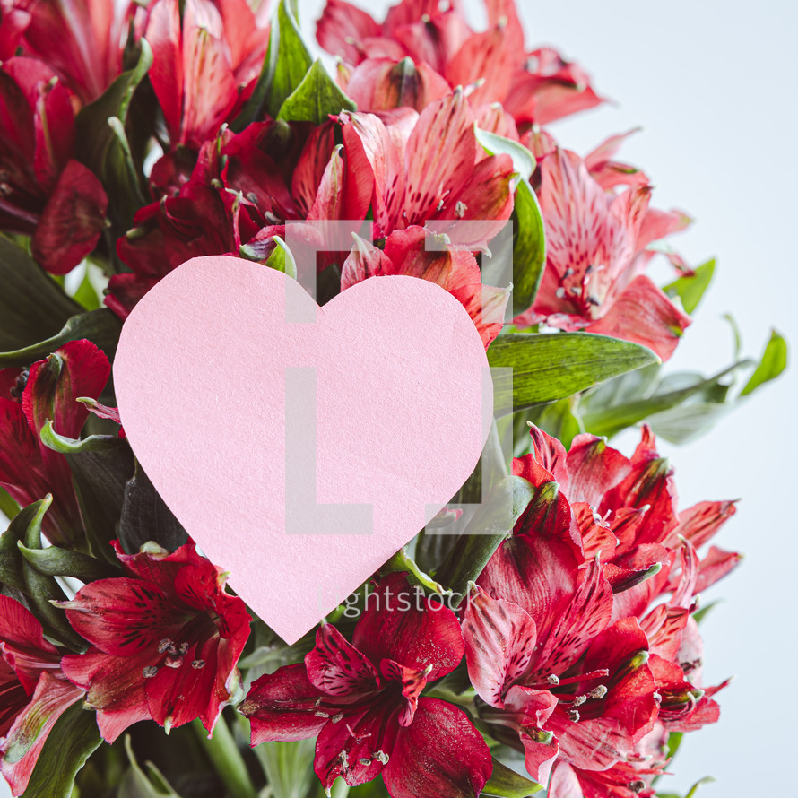 Pink paper heart on flowers