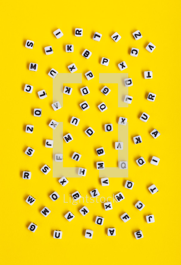White cubes with letters scattered randomly on a yellow background